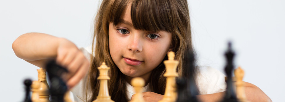 Young caucasian girl with long hair playing a game of chess.